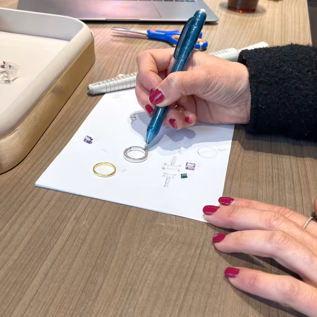 proceso de diseño de joya con boceto a mano y piedras sobre mesa