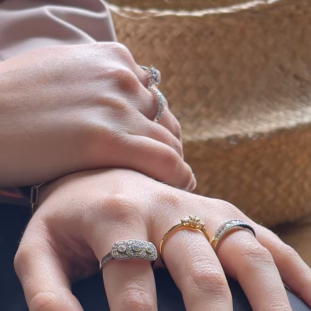 Distintos anillos puestos sobre dos manos vistos desde un ángulo oblicuo.