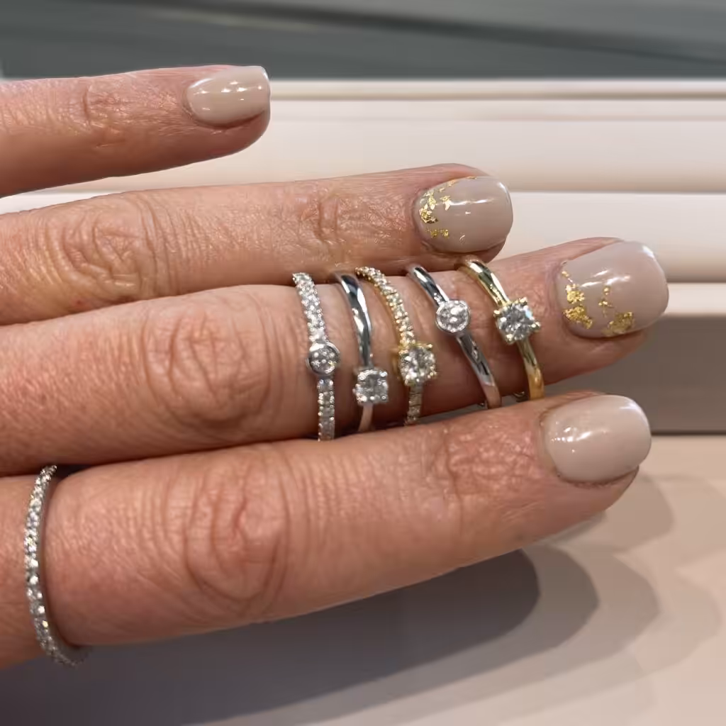Varios anillos de compromiso con distintos niveles de brillo, algunos con bandas lisas y otros con diamantes en la banda.