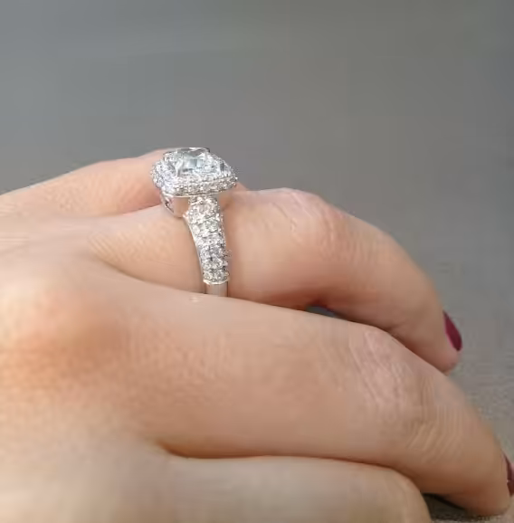Anillo con diamante central, halo y pavé visto de perfil sobre una mano