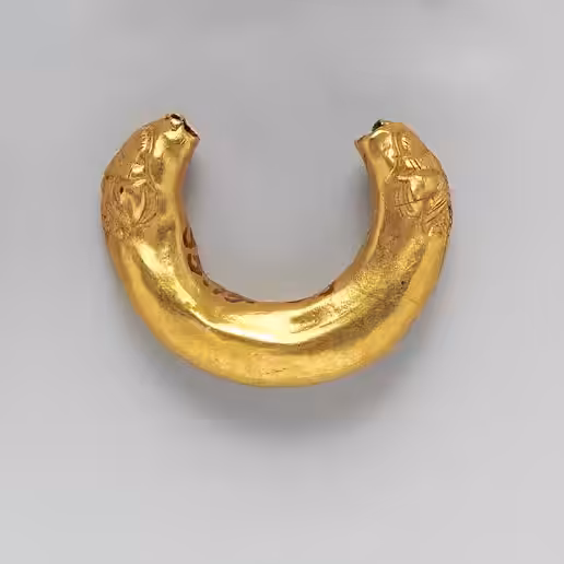 Par de aros antiguos de oro con forma curva y superficie marcada por el paso del tiempo.