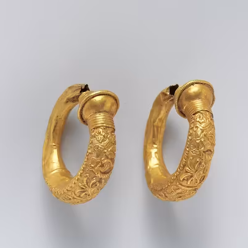 Par de aros antiguos de oro del siglo V–IV a. C., con volumen amplio y detalles decorativos.