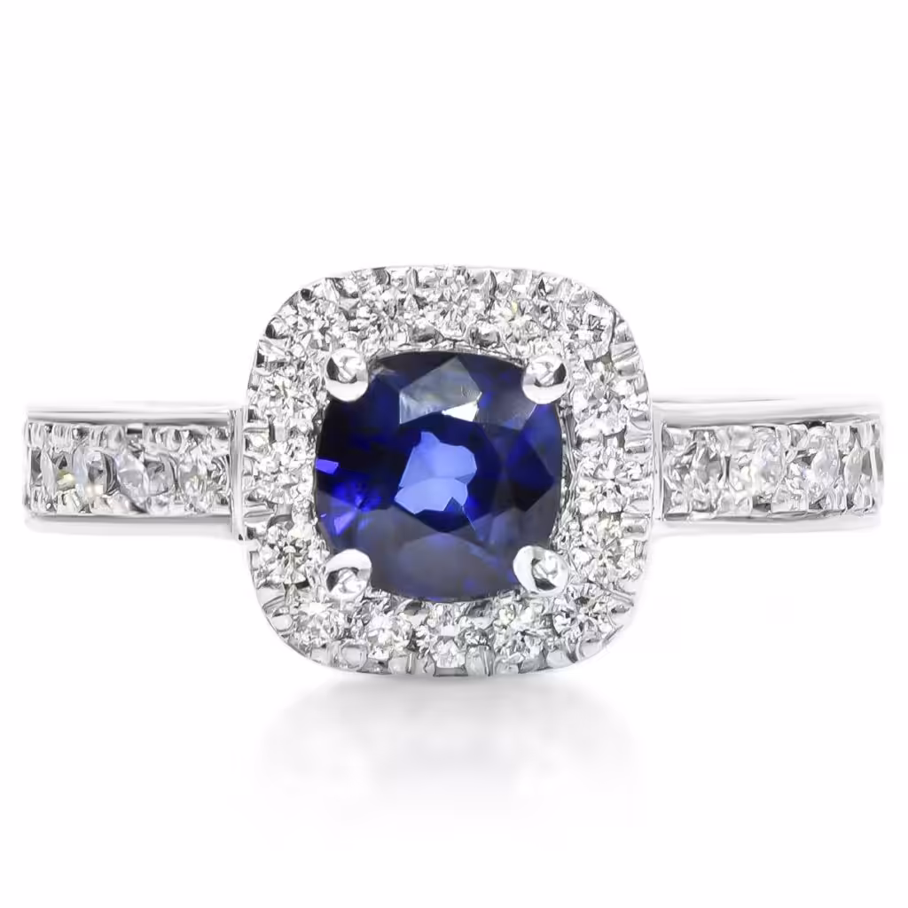 Anillo con zafiro azul central y halo de diamantes.