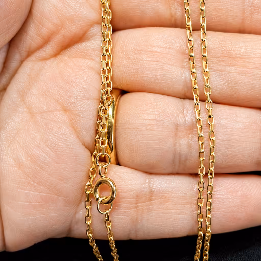 Cadena de oro sobre una mano, con el cierre y las argollas de unión visibles.