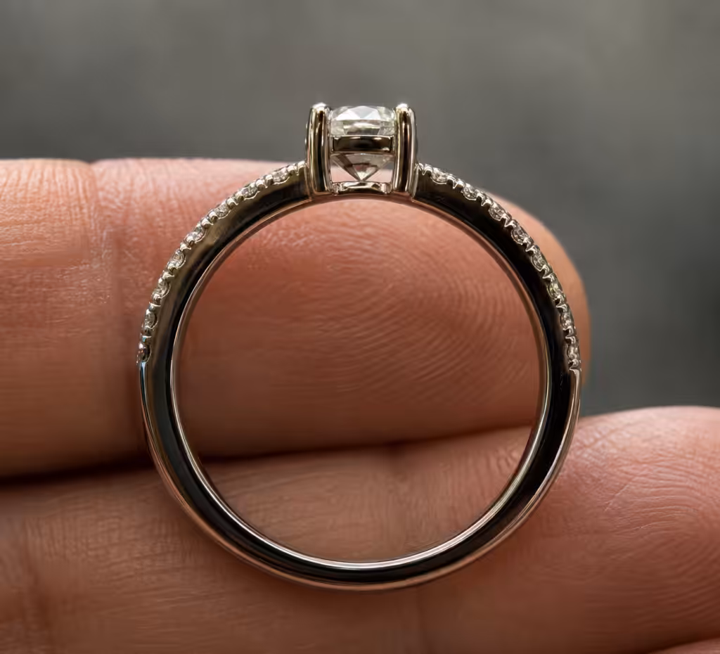 Anillo de diamantes visto de perfil, con la culata del diamante central visible entre las grifas.