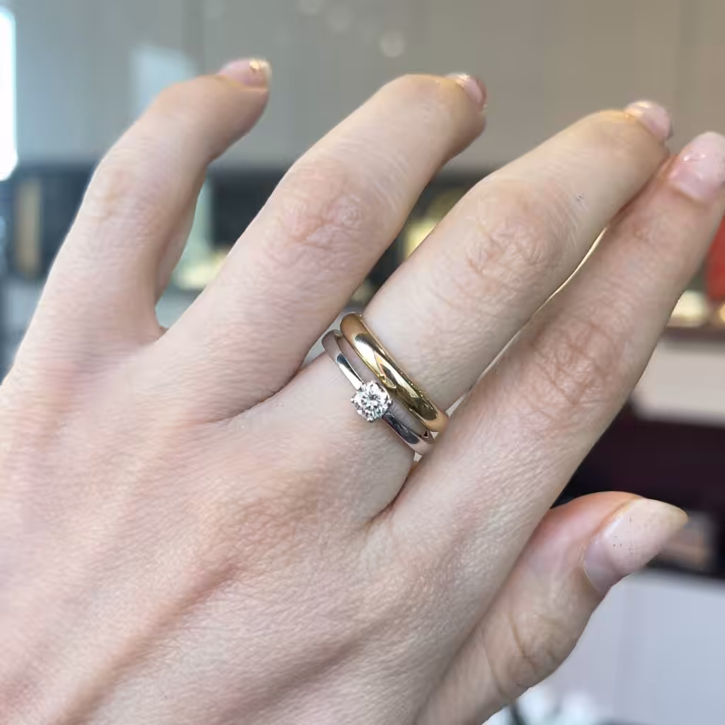 Anillo solitario clásico usado junto a una argolla de matrimonio