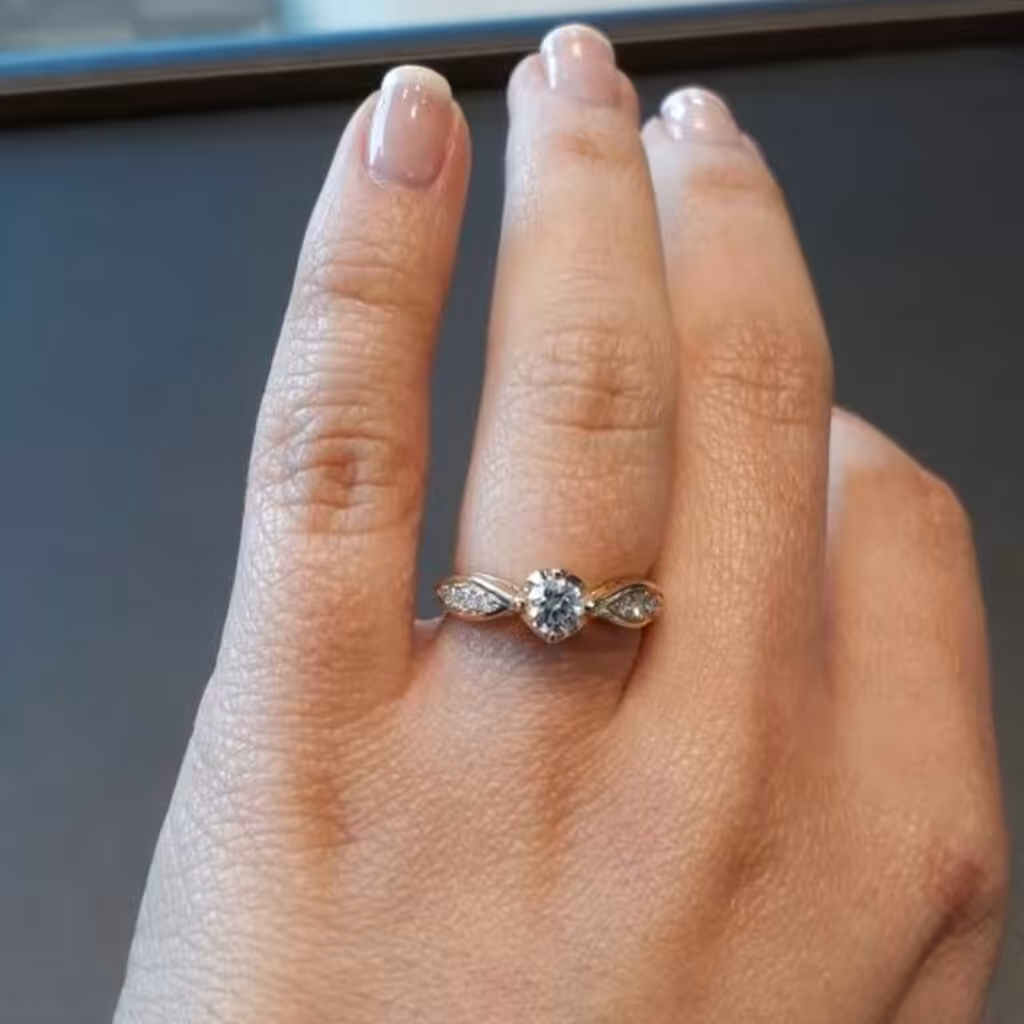 Anillo solitario con piedra central redonda, cabezal compacto y banda lisa sobre un dedo