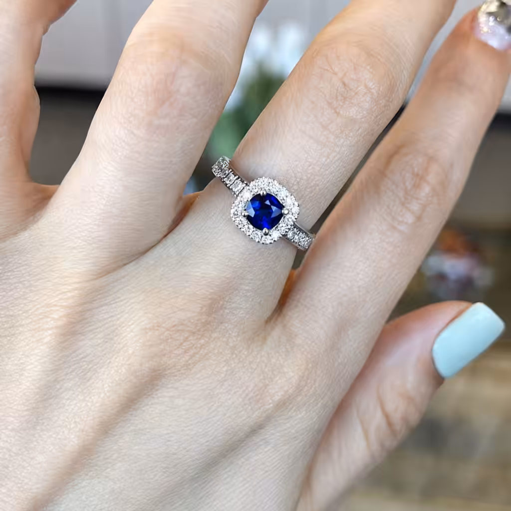 Anillo con zafiro azul central rodeado por un halo de diamantes