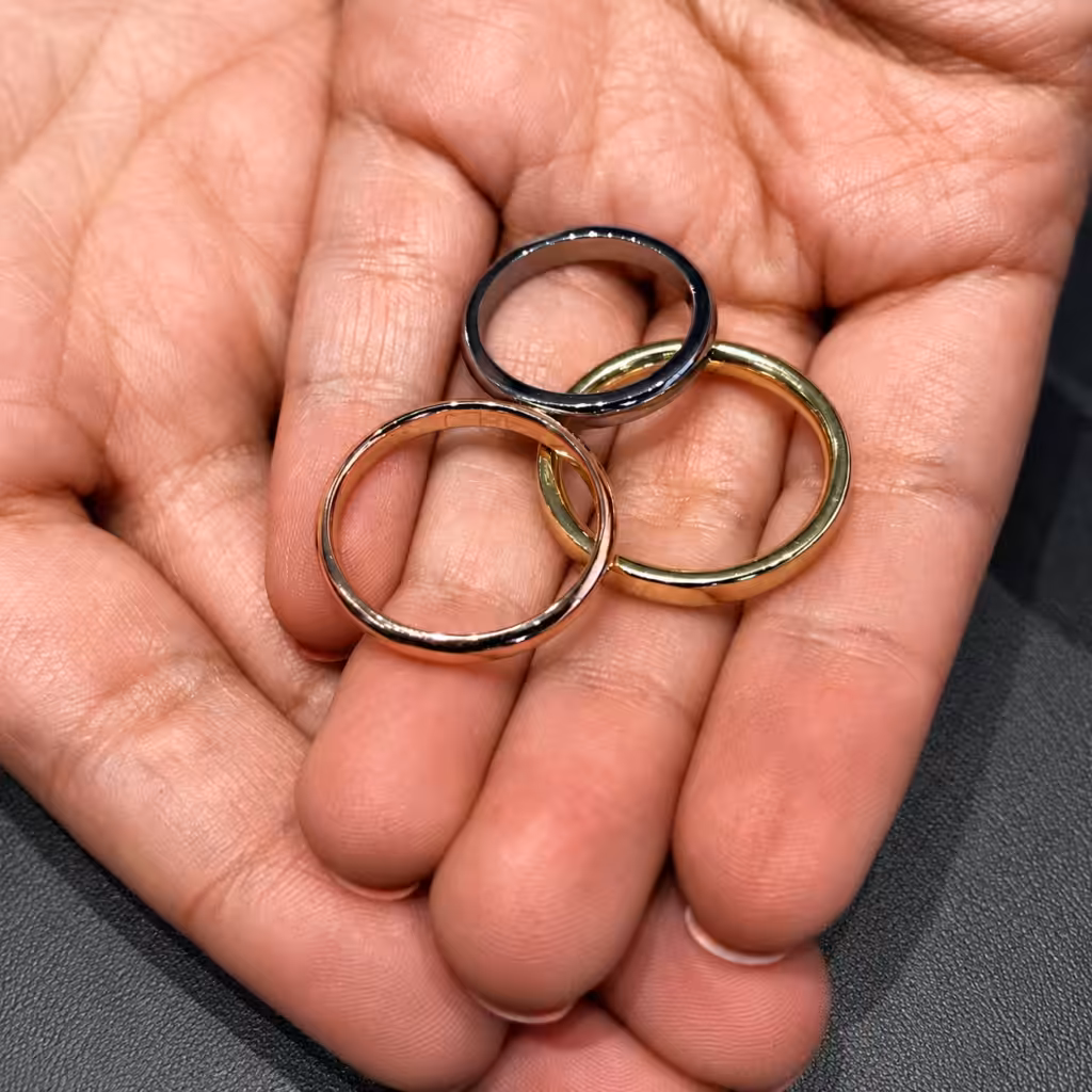 Tres anillos en oro blanco, amarillo y rosado sostenidos sobre una mano.