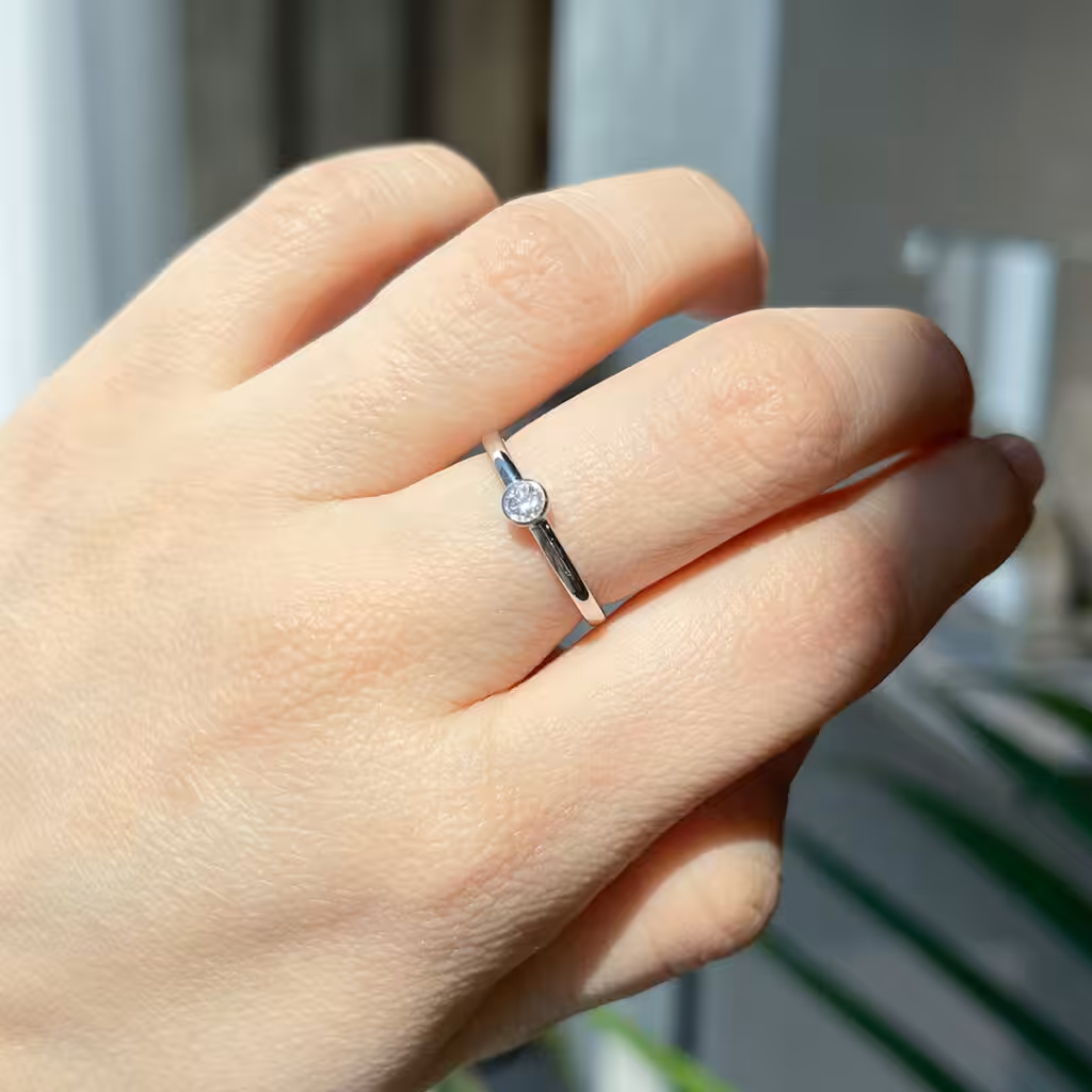 Anillo solitario de banda firme con diamante central en montura baja.
