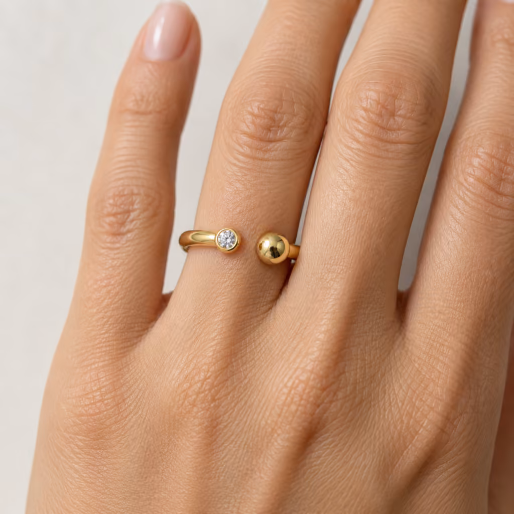 anillo abierto de oro amarillo con un diamante y una esfera en sus extremos.